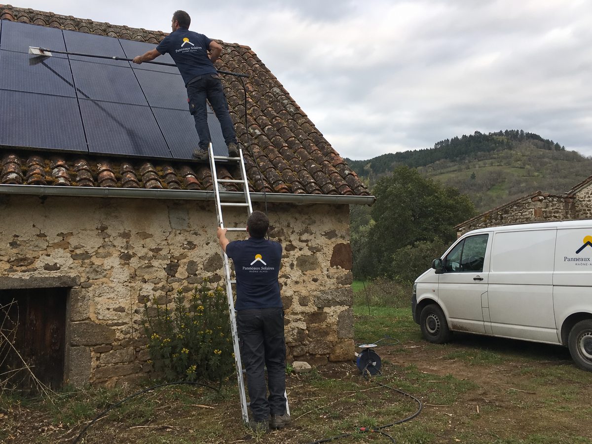 Nettoyage des panneaux sur le toit en tuile canal d'une ferme en pisé