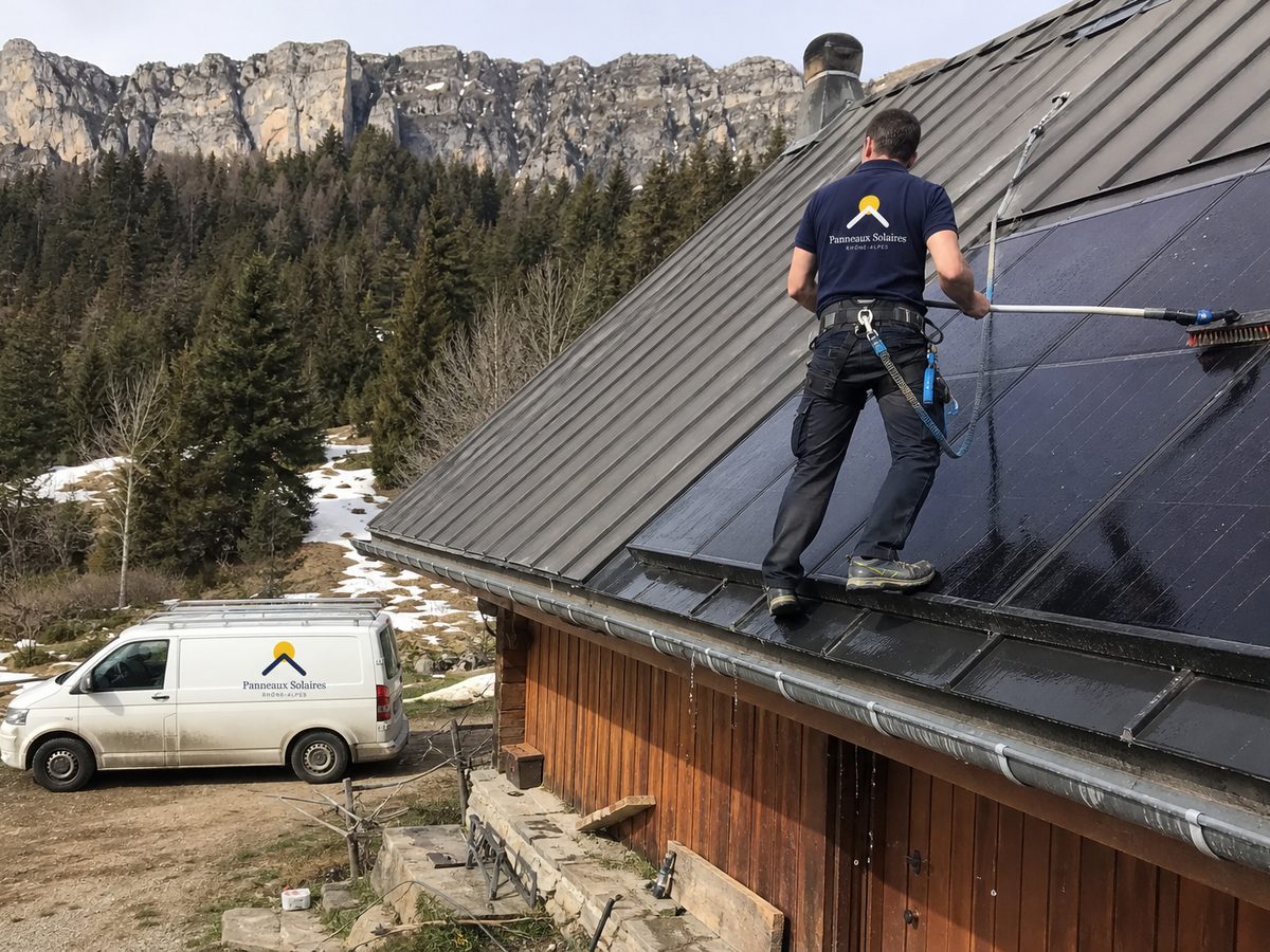 Nettoyage des panneaux sur le toit en tôle d'un chalet, après la fonte des neiges