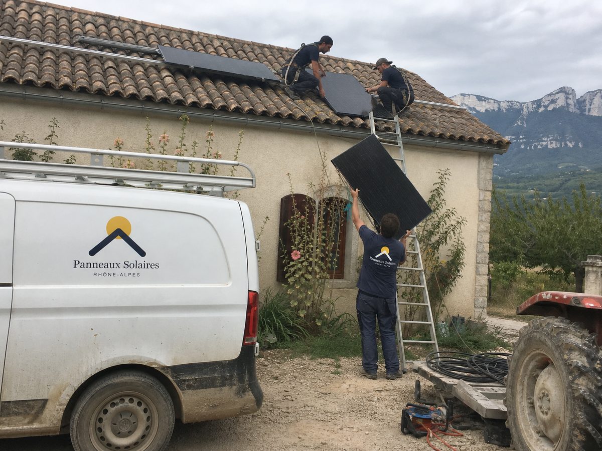 Pose de panneaux sur une ferme au milieu des vergers, des falaises au loin