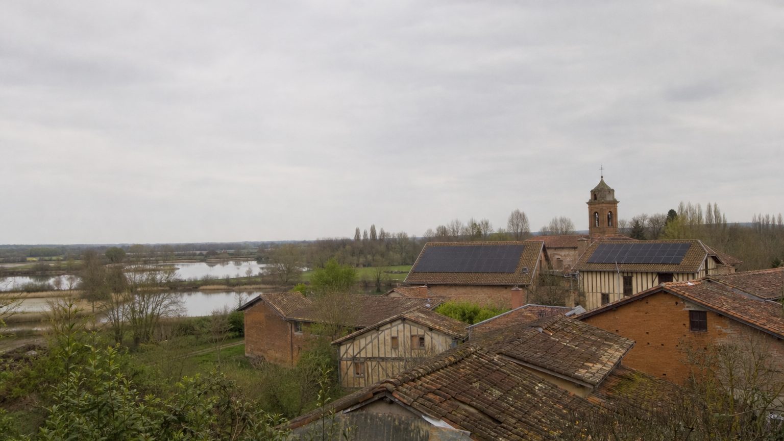 Campagne plate d'étangs et de fermes en brique à pans de bois, deux toits équipés de panneaux