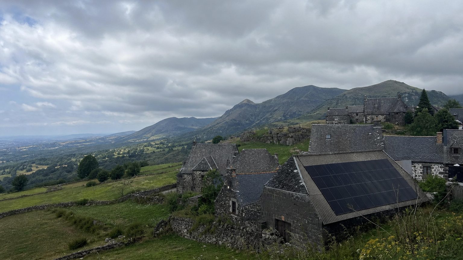 Hautes terres volcaniques, maisons de basalte aux toits de lauze, une grange équipée de panneaux