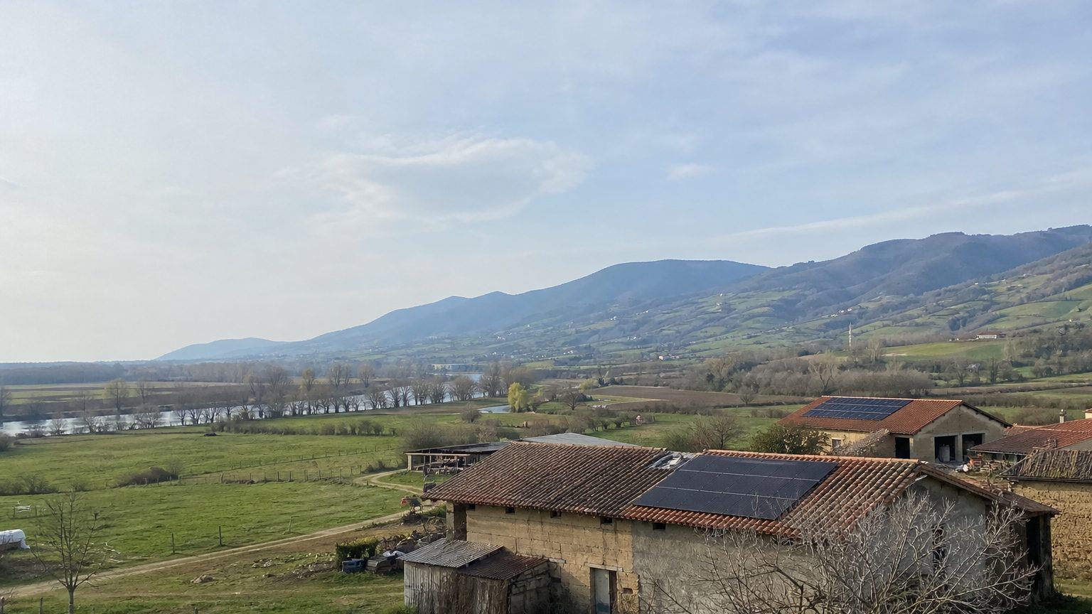 Plaine agricole, fermes en pisé et monts boisés, deux toits équipés de panneaux