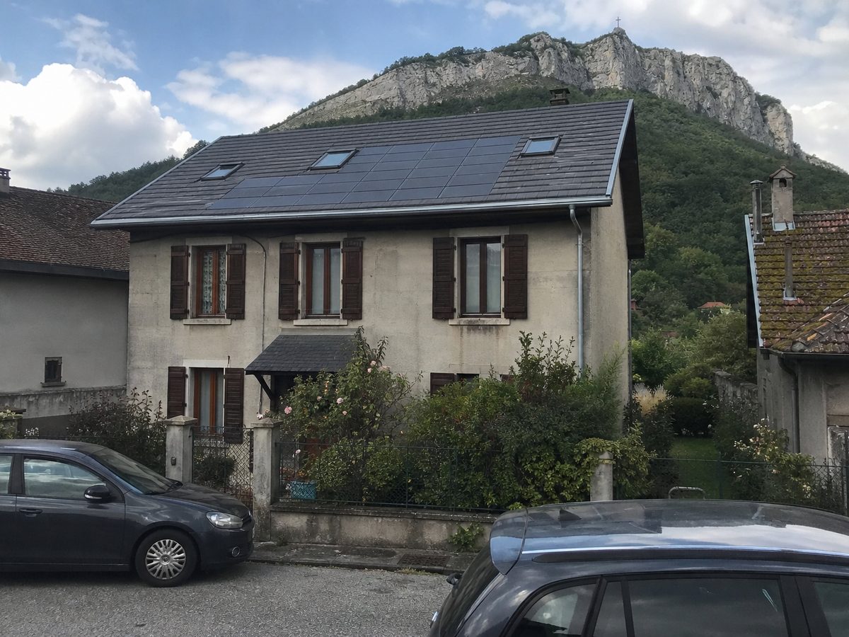 Maison des années 1930 à Chambéry, tuiles solaires intégrées au pan sud de la toiture neuve, le Nivolet et sa croix derrière
