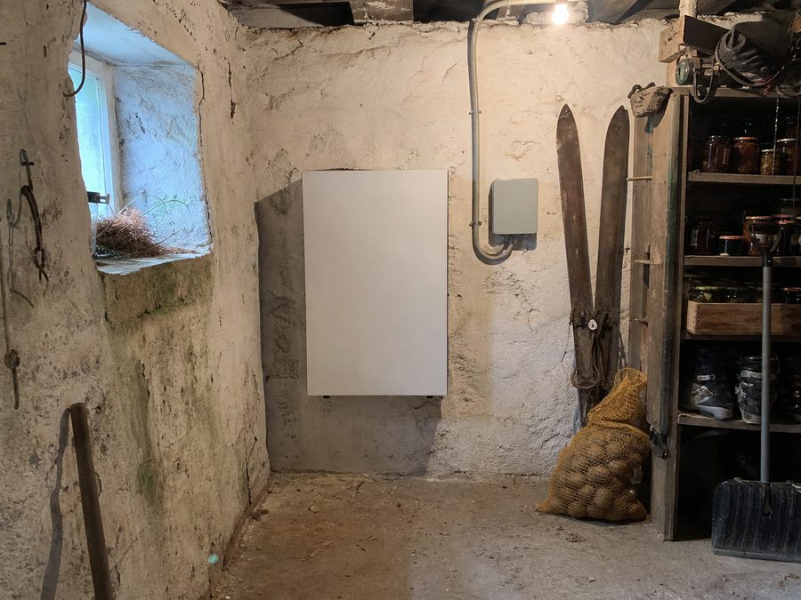 La batterie fixée au mur du cellier, entre les étagères de bocaux et les chaussures de ski