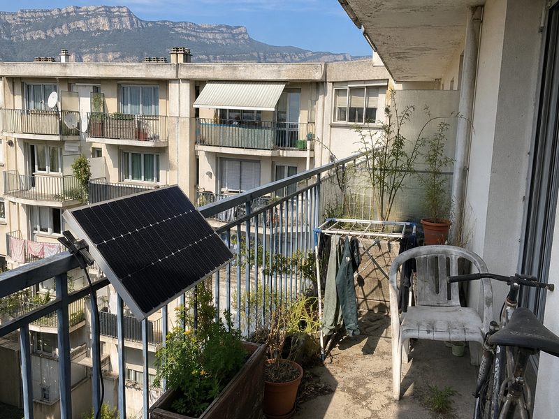 Panneau solaire accroché à la rambarde d'un balcon d'immeuble de la banlieue grenobloise