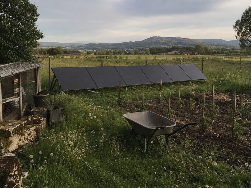 Rangée de panneaux au sol au fond d'un potager, dans la plaine de la Bièvre